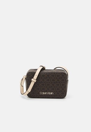 Ciemnobrązowa torebka Calvin Klein na ramię z beżowym regulowanym paskiem, z powtarzającym się wzorem monogramu "ck" oraz złotym logo z przodu.