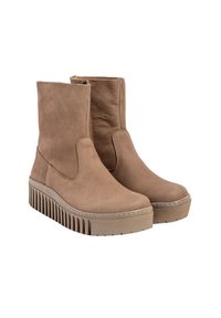 Botas de tobillo de color beige hechas de cuero suave, con una cremallera lateral y una suela de plataforma gruesa y texturizada con rayas verticales.