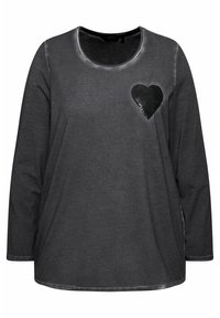 Grijs shirt met lange mouwen en een ronde hals, voorzien van een zwart sequins hart op de linkerborst en een iets gebogen zoom. Zachte textuur.