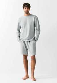 Gray long-sleeve sweatshirt and matching shorts made of soft fabric. Casual design with a relaxed fit and elastic waistband on shorts.
