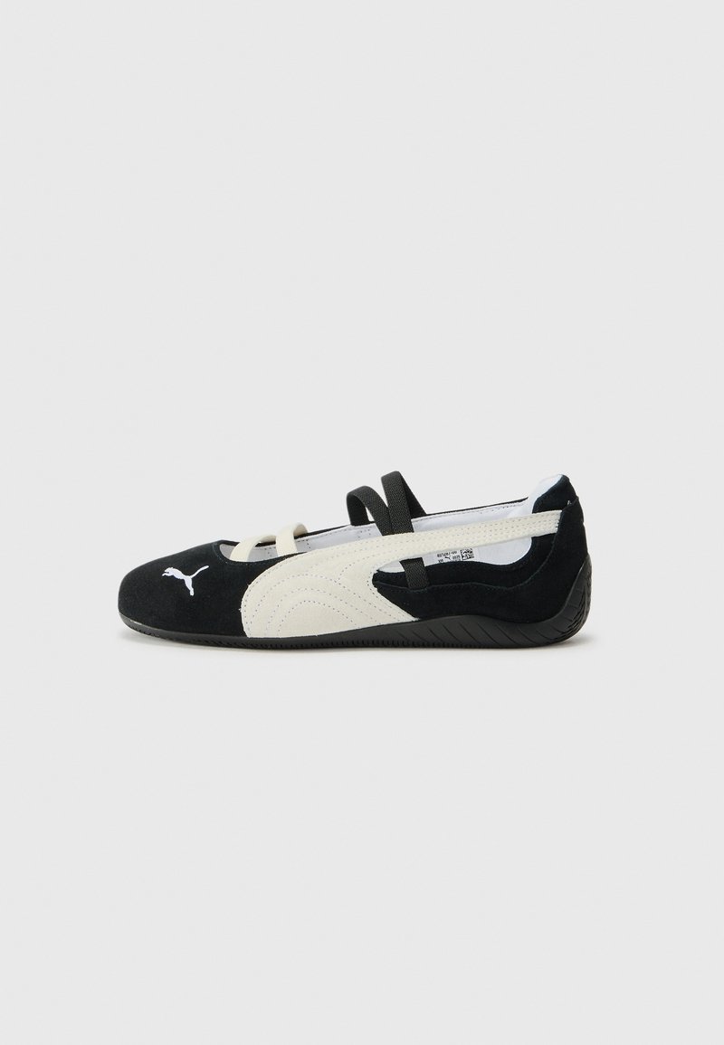 Zwarte en crèmekleurige ultralichte schoen met een leren bovenkant, platte zool, elastische banden en een klein logo op de teen.
