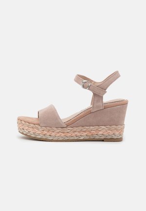 Beige ruskinds kile sandal med ankelrem og flettet repdetalje på platformsålen mod en hvid baggrund.