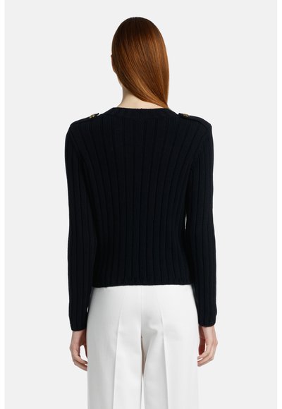 Marineblauwe geribbelde gebreide trui met lange mouwen, cropped lengte en gouden hardware accenten op de schouders. Zachte textuur en aansluitend ontwerp.