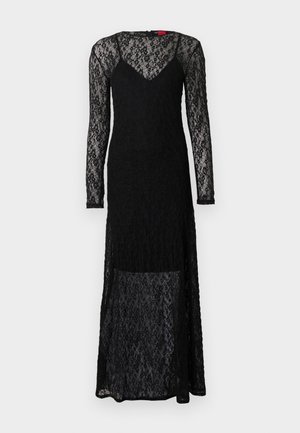 Svart spetsklänning med långa ärmar, en v-ringning och genomskinlig textur. Har en figurnära överdel och en flödande, lager-på-lager kjol.