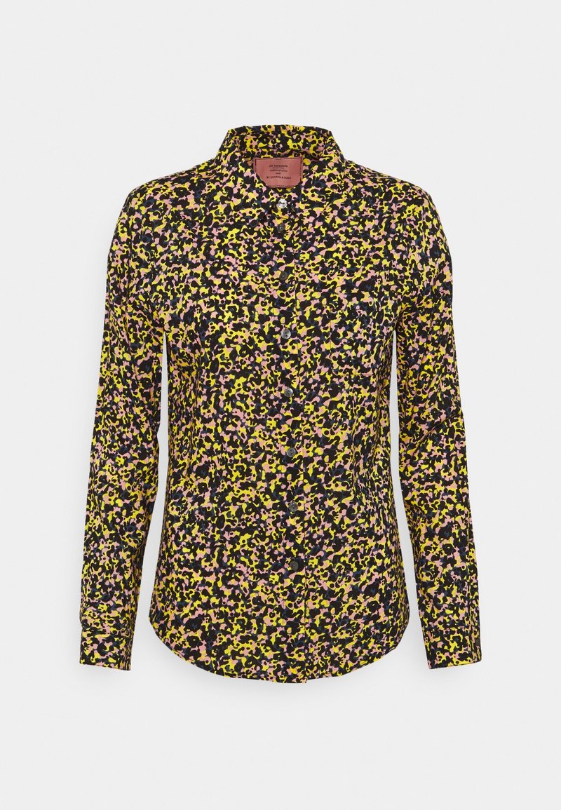 Chemise à manches longues boutonnée avec un motif floral abstrait multicolore en jaune, rose et noir sur fond blanc.