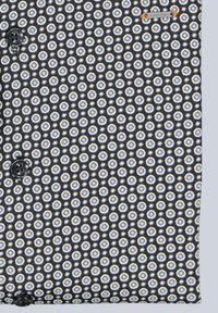 Schwarzer Stoff mit einem geometrischen Muster aus kleinen weißen Kreisen mit blauen Akzenten. Schwarze Knöpfe sind an dem Kleidungsstück sichtbar.