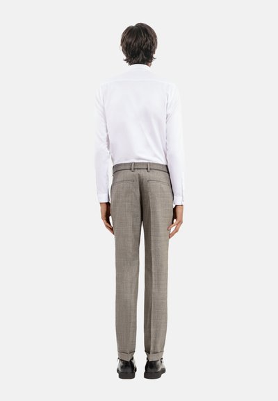Weißes Langarmshirt mit geradem Schnitt, kombiniert mit grauen karierten Hose. Die Hose hat eine glatte Textur und zwei Gesäßtaschen.