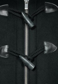 Cappotto di lana nero con zip argentata, dettagli in pelle nera, lacci intrecciati neri e chiusure con toggles distintivi.