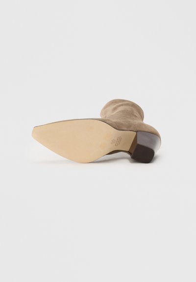Brown suede ankle boot with a pointed toe and a short block heel. The sole is beige with subtle branding details near the heel.
