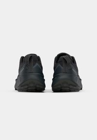Chaussures de sport noires avec tige en tissu texturé, col rembourré et semelle en caoutchouc durable dotée de motifs de traction profonds. Boucles au talon renforcées.