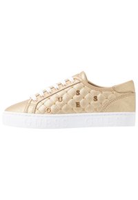 Sneaker oro trapuntate con lacci bianchi e suola bianca. Materiale sintetico lucido e logo del marchio in rilievo sulla suola e sul lato.