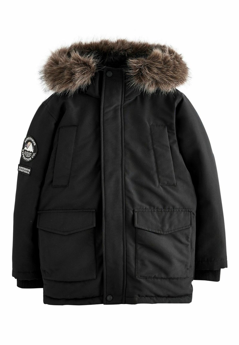 Čierna parka bunda s kožušinovou kapucňou, obsahujúca dve predné vrecká s klopou, rebrované manžety a nášivku s logom na ľavom rukáve.