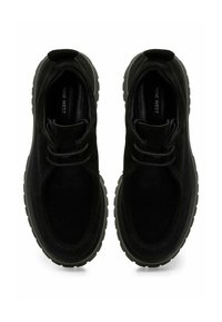 Zapatillas de ante negro con forma redondeada, parte superior texturizada, suela de goma y cordones dobles. Incluye una etiqueta con el logotipo en el interior de la zapatilla.