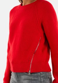 Maglione rosso lavorato a maglia con texture a costine, scollo rotondo e dettaglio con zip sul lato. Design aderente, maniche a lunghezza intermedia e vestibilità casual.