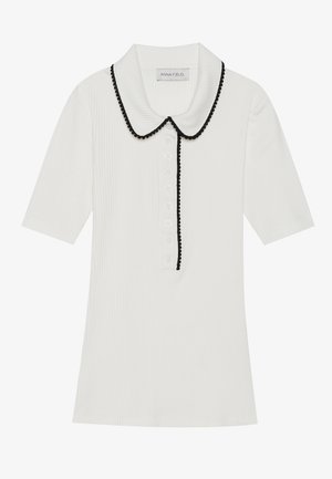 Haut blanc à manches courtes côtelé avec col noir à volants et fermeture à boutons sur le devant. Présente un tissu texturé et une coupe ajustée.