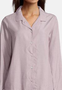 Blusa a maniche lunghe di un leggero colore lavanda con colletto a puntale, sette bottoni sul davanti e un tessuto liscio e testurizzato.