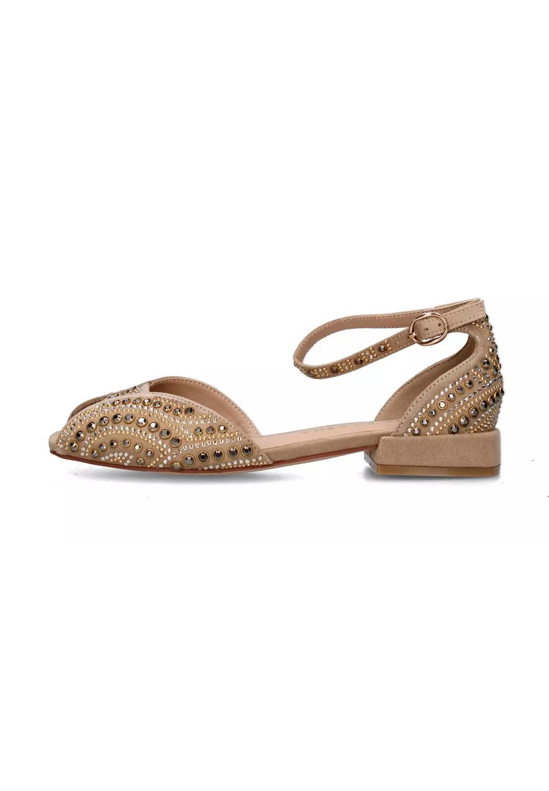 Scarpa flat beige con punta aperta, decorata con borchie dorate e argentate, dotata di una cinghia attorno alla caviglia e un tacco basso a blocco.