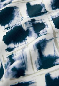 Tissu fluide avec un motif abstrait bleu marine et blanc, incorporant des textures de coups de pinceau et des formes en grille tout au long.