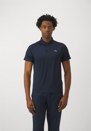 Polo shirt blu navy, maniche corte, con colletto classico. Presenta un logo ricamato verde sul petto. Realizzato in un tessuto liscio e traspirante.