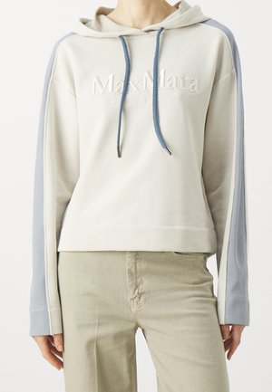 Persoon draagt een crème hoodie met blauwe zijstrepen en blauwe koordjes, met het "MaxMara Leisure" logo op de borst.
