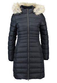 Manteau rembourré noir avec une capuche en fausse fourrure, fermeture éclair à l'avant, texture côtelée et poches latérales. Dispose d'une silhouette ajustée et d'un design mi-long.