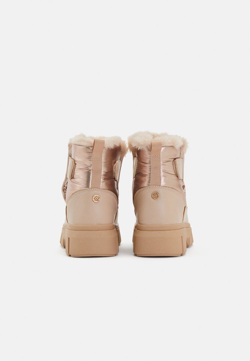 Stivali alla caviglia color oro rosa con tomaia lucida e imbottita, fodera in pelliccia sintetica e suola in gomma beige. Presenta una linguetta sul retro e un dettaglio con logo rotondo.