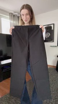 Svarte bukser holdt opp vertikalt, med en jevn tekstur og rett snitt. Stoffet ser lett ut med elastisk midje.