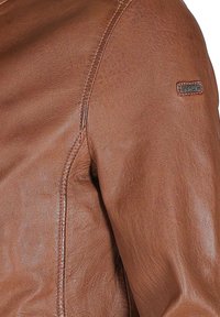 Braune Lederjacke mit glatter Textur, sichtbaren Nähten und einem markierten Lederpatch am Ärmel.