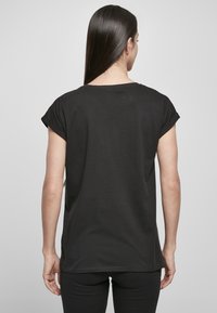 Black cotton t-shirt with rolled sleeves, round neckline, and a loose fit. Smooth texture, no patterns or graphics visible.