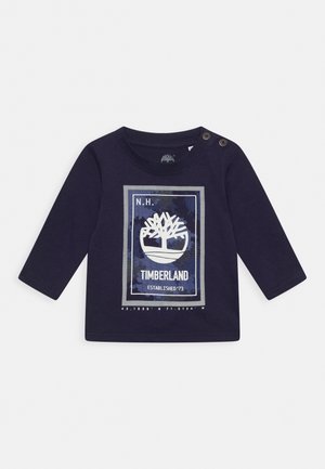Camiseta de algodón de manga larga en color navy, con un logo de árbol, estampado gráfico y dos botones en el hombro para facilitar su uso.