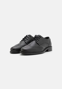 Scarpe da uomo in pelle nera, con superficie liscia, design wingtip caratterizzato da dettagli perforati e tacco basso a blocco. Chiusura con lacci.