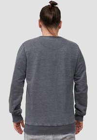 Sudadera gris de tejido suave, con mangas largas y dobladillo acanalado. Diseño sencillo con cuello redondo y acabado texturizado.