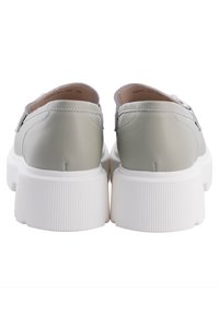 Paire de chaussures grises claires sans lacets avec des semelles plateformes épaisses blanches texturées, vues de dos sur fond blanc.