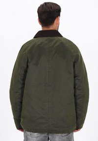 Olivengrøn, polstret jakke med en kordfløjskrave, drop shoulder design og diskrete sømdetaljer på ryggen.