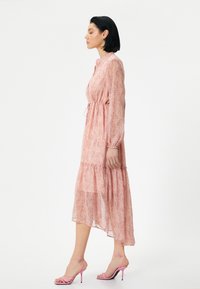 Roze bloemen midi-jurk met lange mouwen, trekkoord in de taille en tiered zoom. Gepaard met roze slipperhakken. Zachte, lichte stof.