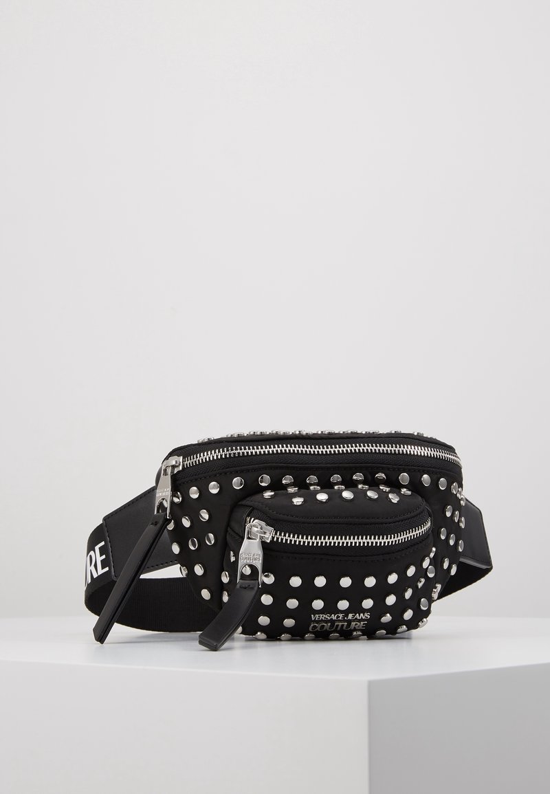 Marsupio nero con borchie argento, doppia cerniera, cinturino regolabile e dettaglio del logo. Tessuto morbido con una finitura testurizzata, design compatto.