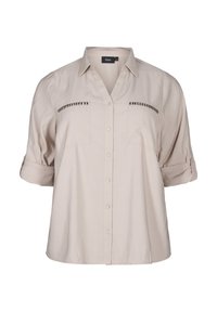 Camicia leggera beige, con maniche corte, collo a V, due tasche sul petto e decorazioni di borchie sui taschini.