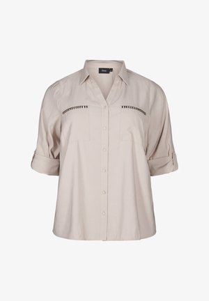 Camicia leggera beige, con maniche corte, collo a V, due tasche sul petto e decorazioni di borchie sui taschini.