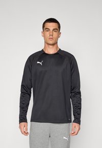Svart langermet treningstrøye med rund hals, laget av glat stoff. Har en hvit Puma-logo på brystet og teksturerte skulderpaneler.