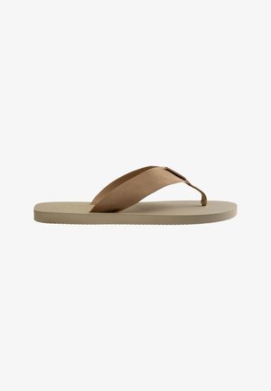 Beige Flip-Flop-Sandale mit strukturierter Sohle und breitem braunem Stoff-Zehentrennriemen auf weißem Hintergrund.