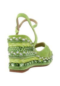 Groene suède wedge sandaal met gevlochten details, versierd met groene en zilveren kralen, en een band rond de enkel voor een veilige pasvorm.