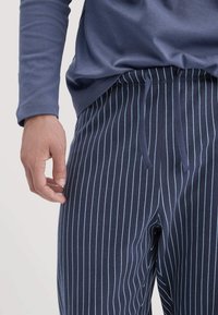 Marine gestreifte Lounge-Hosen mit hellblauen Streifen, ausgestattet mit einem elastischen Bund und verstellbarem Kordelzug. Weiches Baumwollmischgewebe.