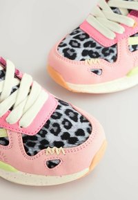 Baskets roses avec une tige en tissu imprimé léopard, des accents en daim texturé et des lacets de couleur claire ; elles présentent une semelle colorée et des coutures décoratives.