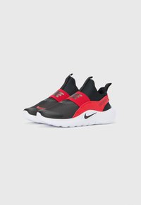 Zapatillas sin cordones Nike en negro y rojo con suelas blancas, correas elásticas rojas con el logo de Nike y texto "Just Do It" en el lateral.