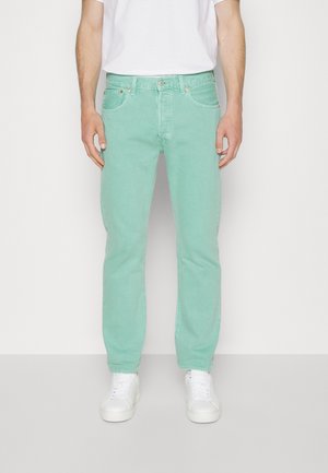 Jeans de mezclilla verde claro con corte recto, cinco bolsillos y detalles de costura sutil, combinados con unas zapatillas blancas y una camiseta blanca lisa.