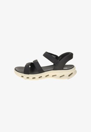 Sort åben-tå sandal med tre justerbare remme og en tyk hvid sål med flere ventilationshuller.