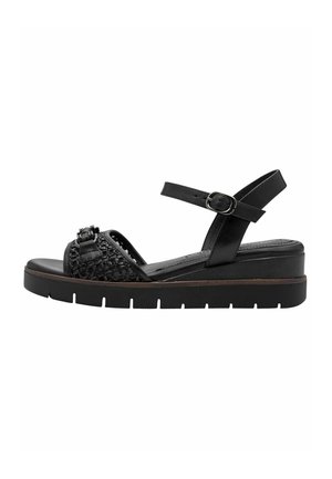 Sort sandal med tyk sål, ankelrem med spænde, vævet frontrem og lille dekorativ knude på tårem.