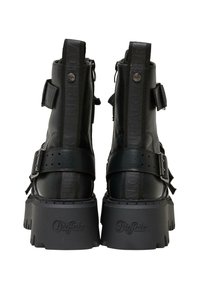 Botas de tobillo de cuero negro con suela gruesa, que cuentan con hebillas, logotipo en relieve y un acabado texturizado en la parte superior.