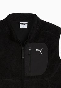 Schwarze Fleece-Weste mit einem Reißverschluss auf der Vorderseite, ausgestattet mit einer linken Brusttasche aus glattem Stoff und einem silbernen Puma-Logo. Strukturierte Oberfläche über die gesamte Weste.