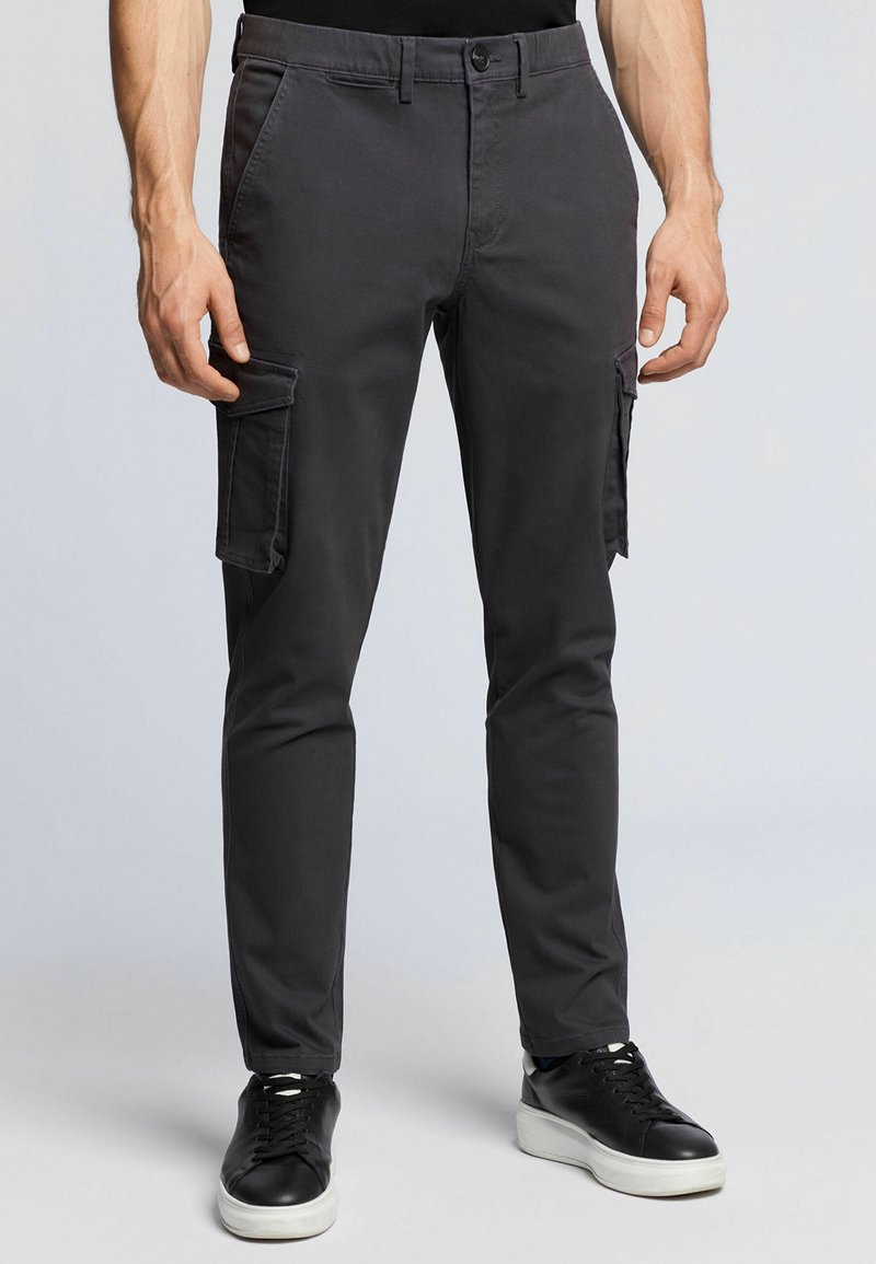 Grå cargobyxor med slim fit, featuring sidofickor, subtil textur och knappstängning, ihop med svarta sneakers.